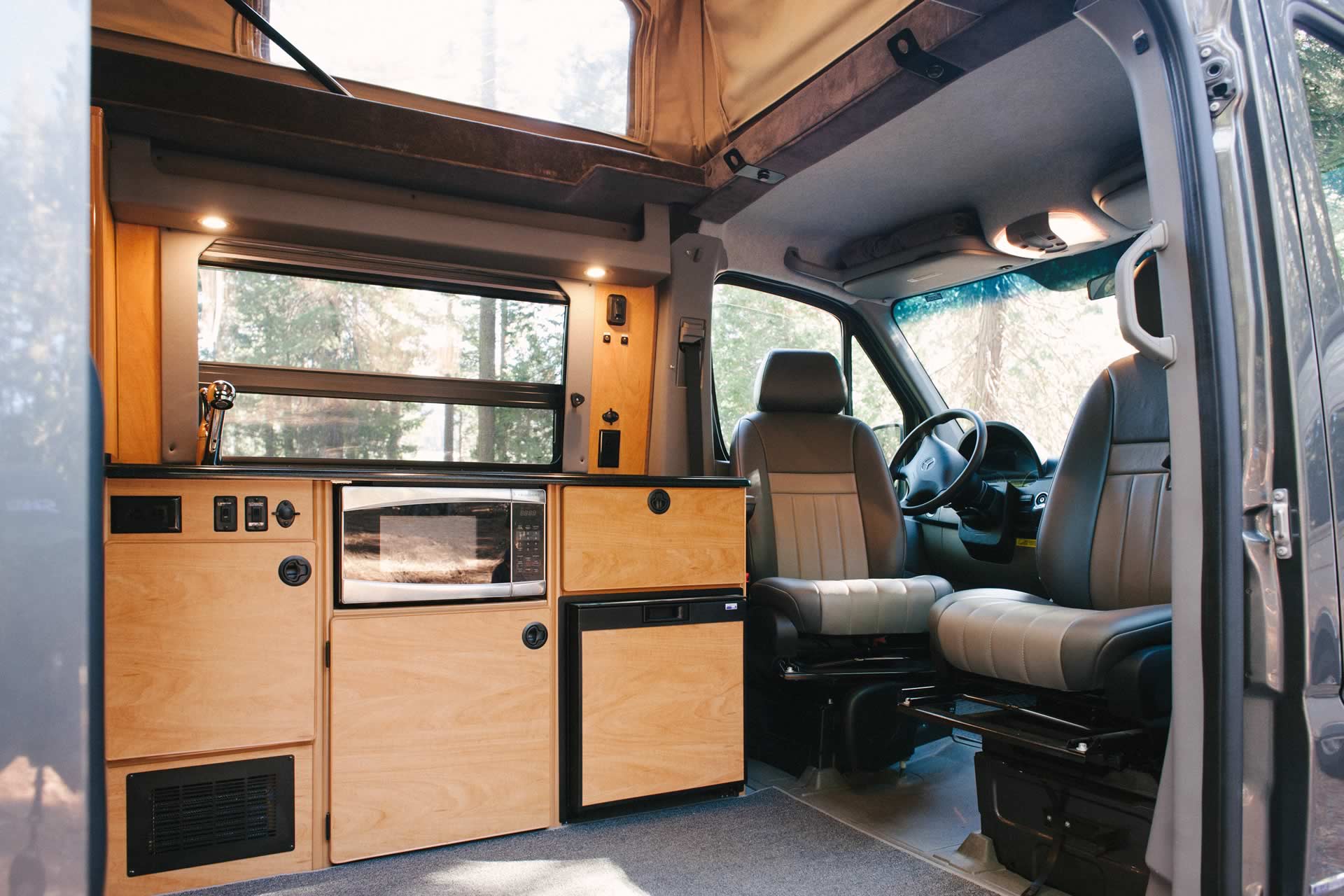 Interior view of Sportsmobile camper van converison with wood cabinets in the galley.