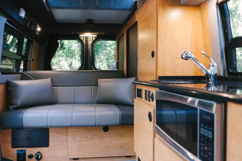 Interior view of Sportsmobile camper van conversion with sofas in the rear.