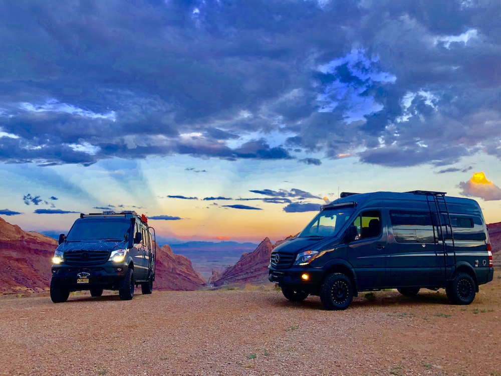 Two black converted Mercedes Sprinter vans parked int the desert.