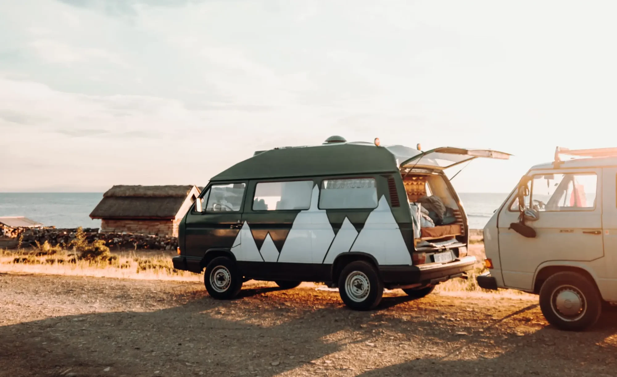 Vans on coastline next to the sea.